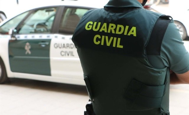 Foto: Archivo - Un agente de la Guardia Civil, de espaldas, junto a un vehículo oficial. - GUARDIA CIVIL